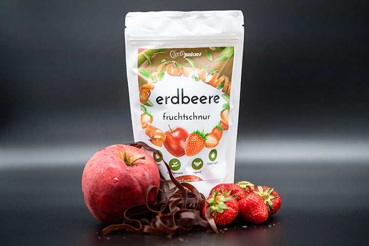 Tüte Fruchtschnur Erdbeere und Erdbeeren sowie eine Apfel und Fruchtschnüre vor der Tüte