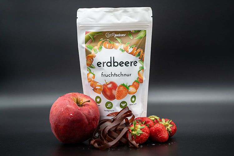 Tüte Fruchtschnur Erdbeere und Erdbeeren sowie eine Apfel und Fruchtschnüre vor der Tüte