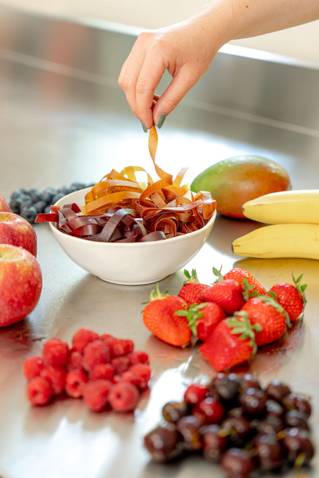 Fruchtschlangen in einer Schale in verschiedenen Geschmacksrichtungen sowie Früchte auf einem Edelstahltisch