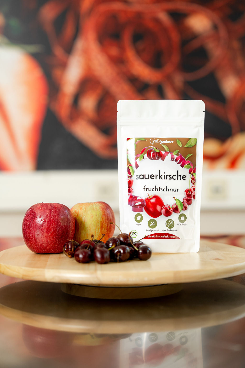 36g Tüte Sauerkirsch Fruchtschnüre auf Drehteller mit Äpfeln und Sauerkirschen